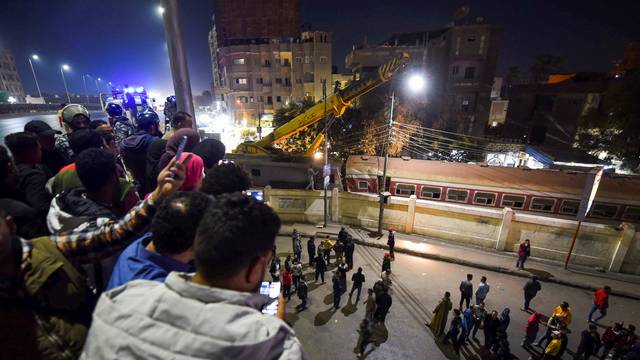 People watch as they gather on a bridge above the scene of a train crash in the city of Qalyub in Al Qalyubia Governorate, north of Cairo