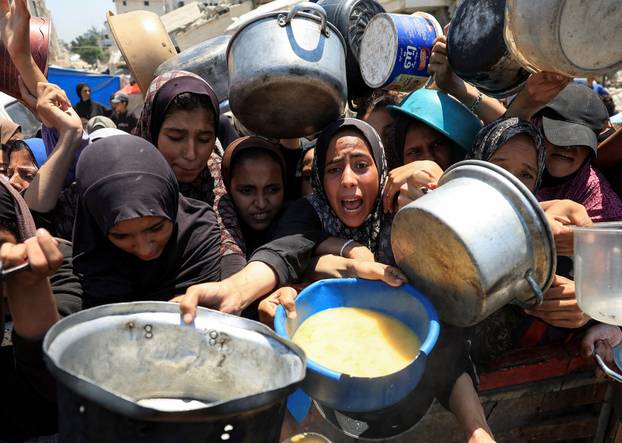 Palestinians wait to receive food from a charity kitchen, in Gaza City