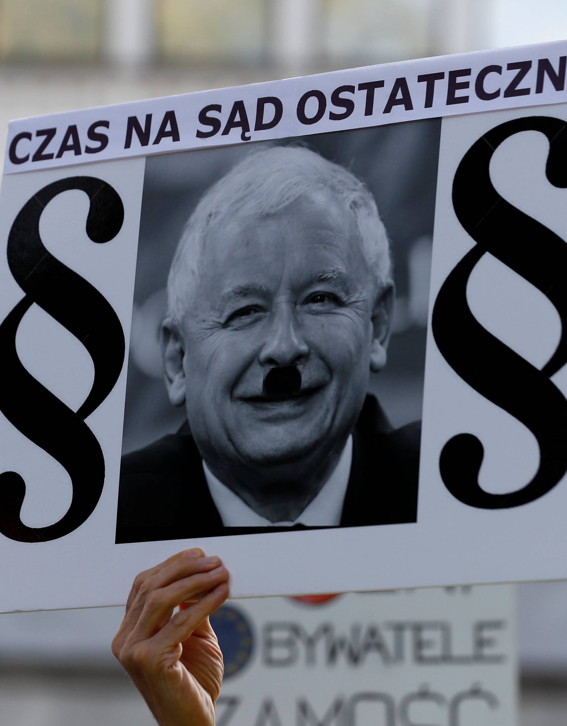 A protester holds a poster with a picture of Law and Justice party leader Jaroslaw Kaczynski and the words "It is time for the Judgement Day" during an anti-government protest in support of free courts in front of the the Senate building in Warsaw