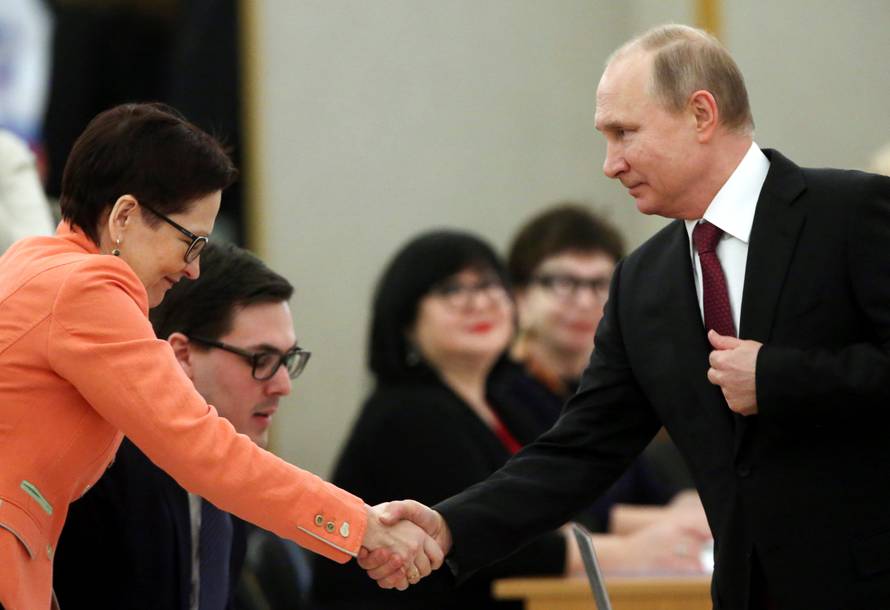 Russian President and Presidential candidate Vladimir Putin shakes hands with a member of a local election commission at a polling station during the presidential election in Moscow