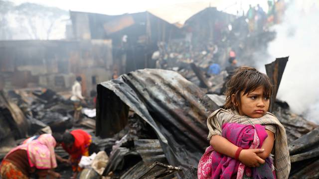 Child looks on, whose shelter has been burned after a fire broke out in a slum in Dhaka