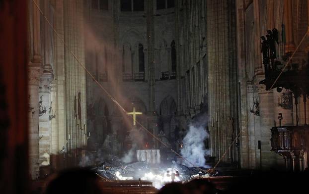 Smoke rises around the alter in front of the cross inside the Notre Dame Cathedral as a fire continues to burn in Paris