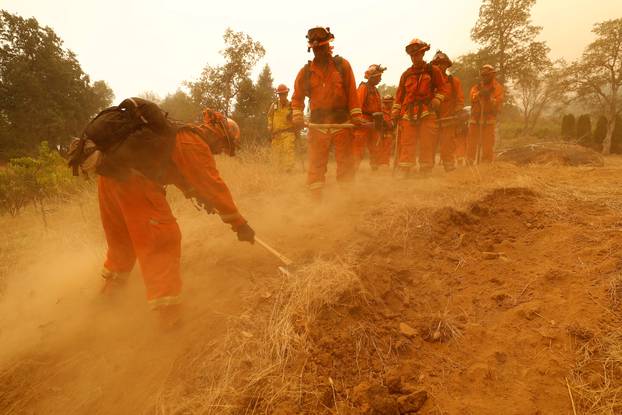 An inmate fire crew cuts fire lines in hot and smoky conditions while working to stop the spread of the Carr Fire, west of Redding, California