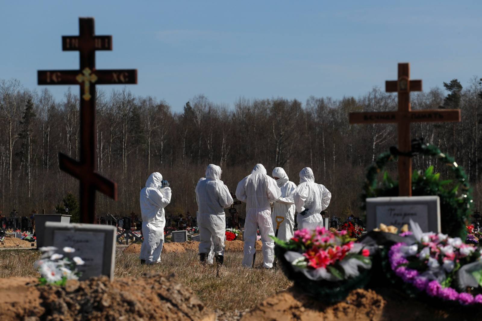 Grave diggers gather after burying a coronavirus disease victim at a graveyard in Saint Petersburg