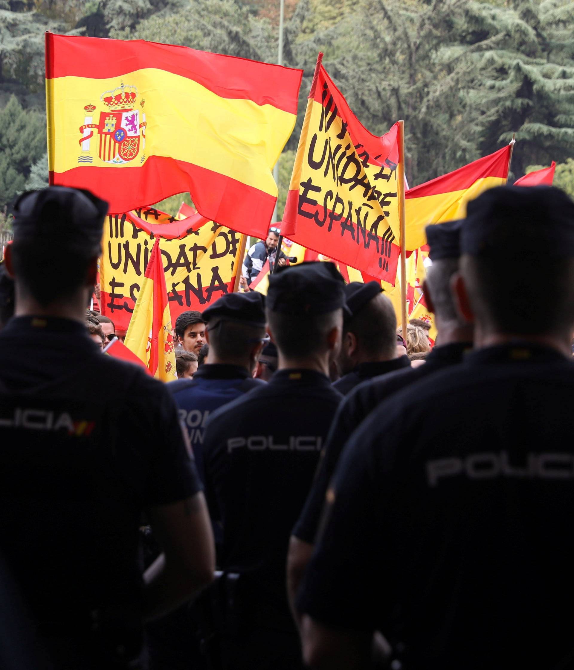 Police stand in front of demonstrators waving Spanish flags in front of city hall during a demonstration in favor of a unified Spain a day before the banned October 1 independence referendum, in Madrid