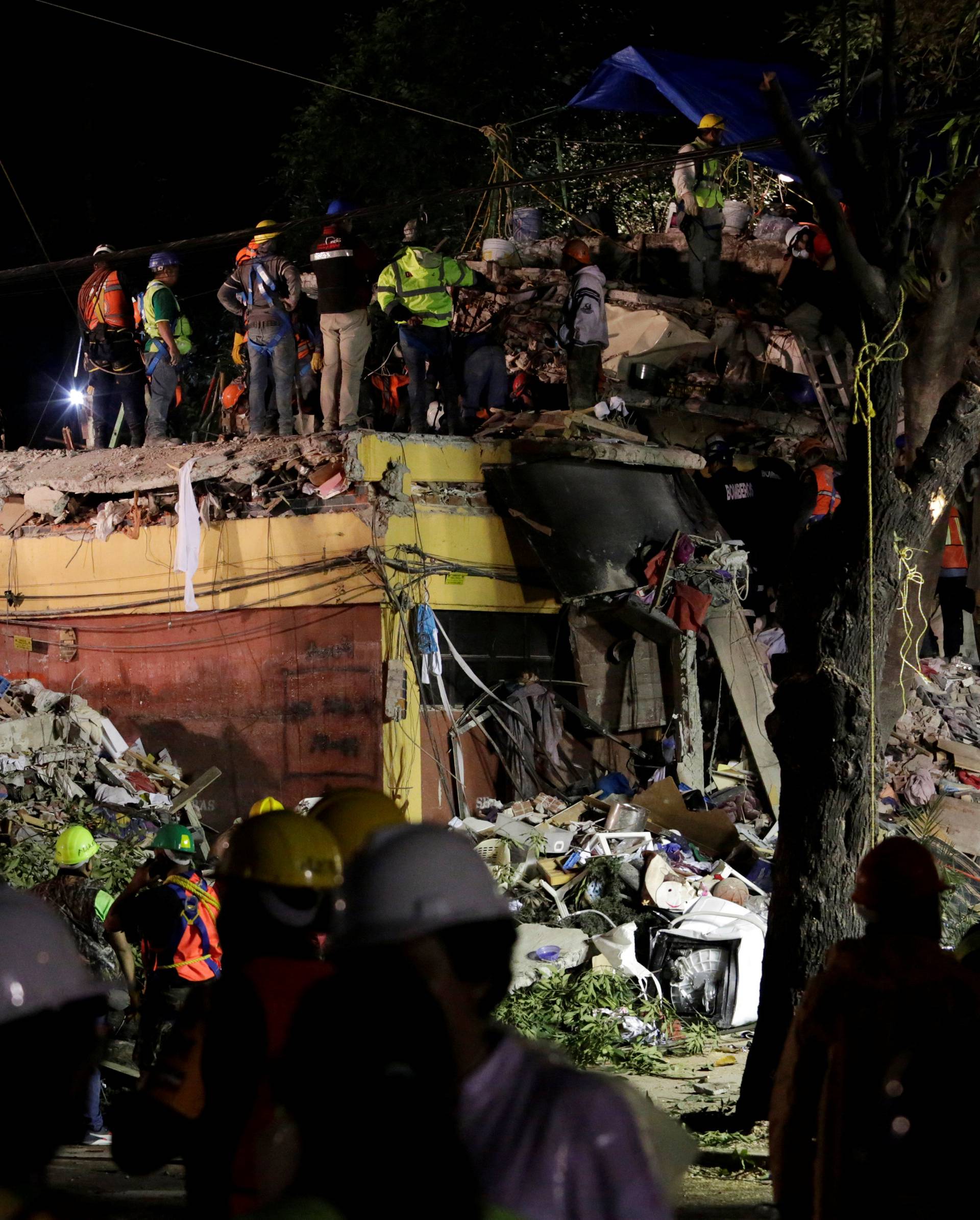 Rescue workers stand on the rubble of a collapsed multi family residential after an earthquake in Mexico City,