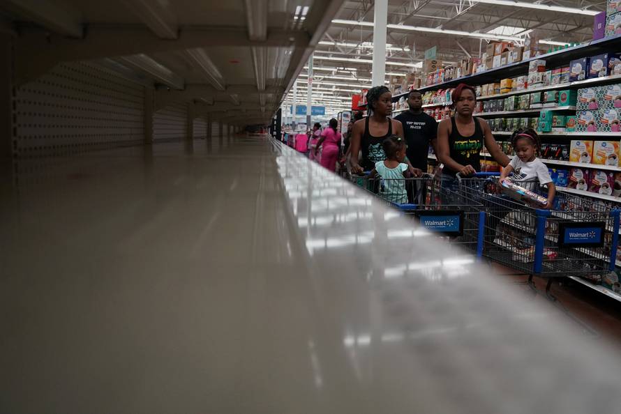 People walk past empty shelves where bread is normally sold in a Walmart store in advance of Hurricane Irma's expected arrival in North Miami Beach