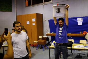Poll workers celebrate after polls close at a polling station for the banned independence referendum in Barcelona