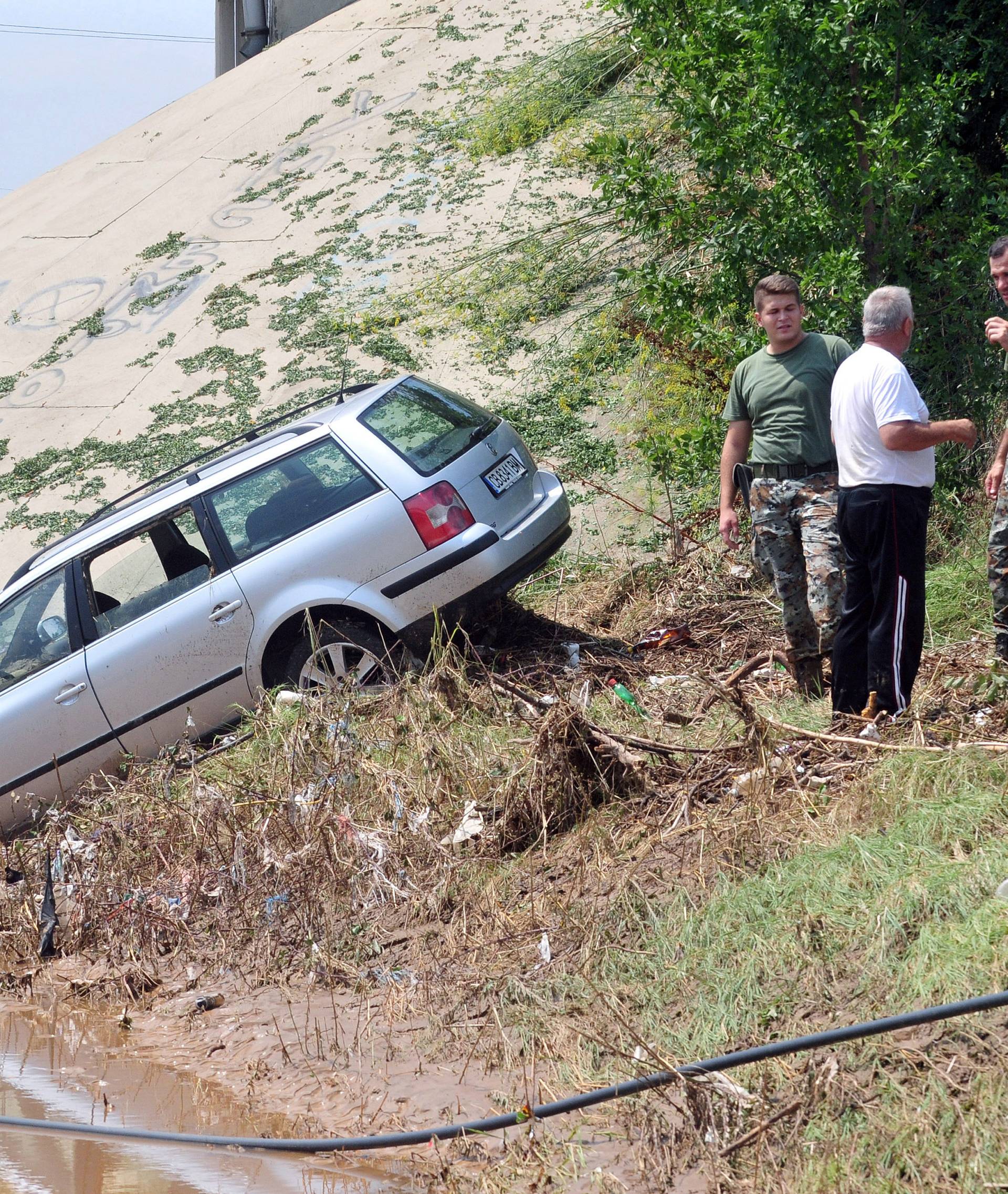 People look at a wrecked car after heavy floods in Cento near Skopje