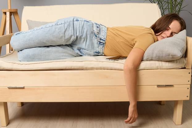 Exhausted Caucasian woman lying on sofa in living room sleeping after hard-working day tired female falling asleep on couch at home, take nap or daydream.