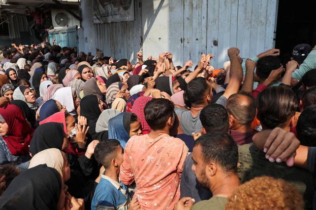 Palestinians gather as they wait to buy bread from a bakery, in Deir Al-Balah, central Gaza Strip