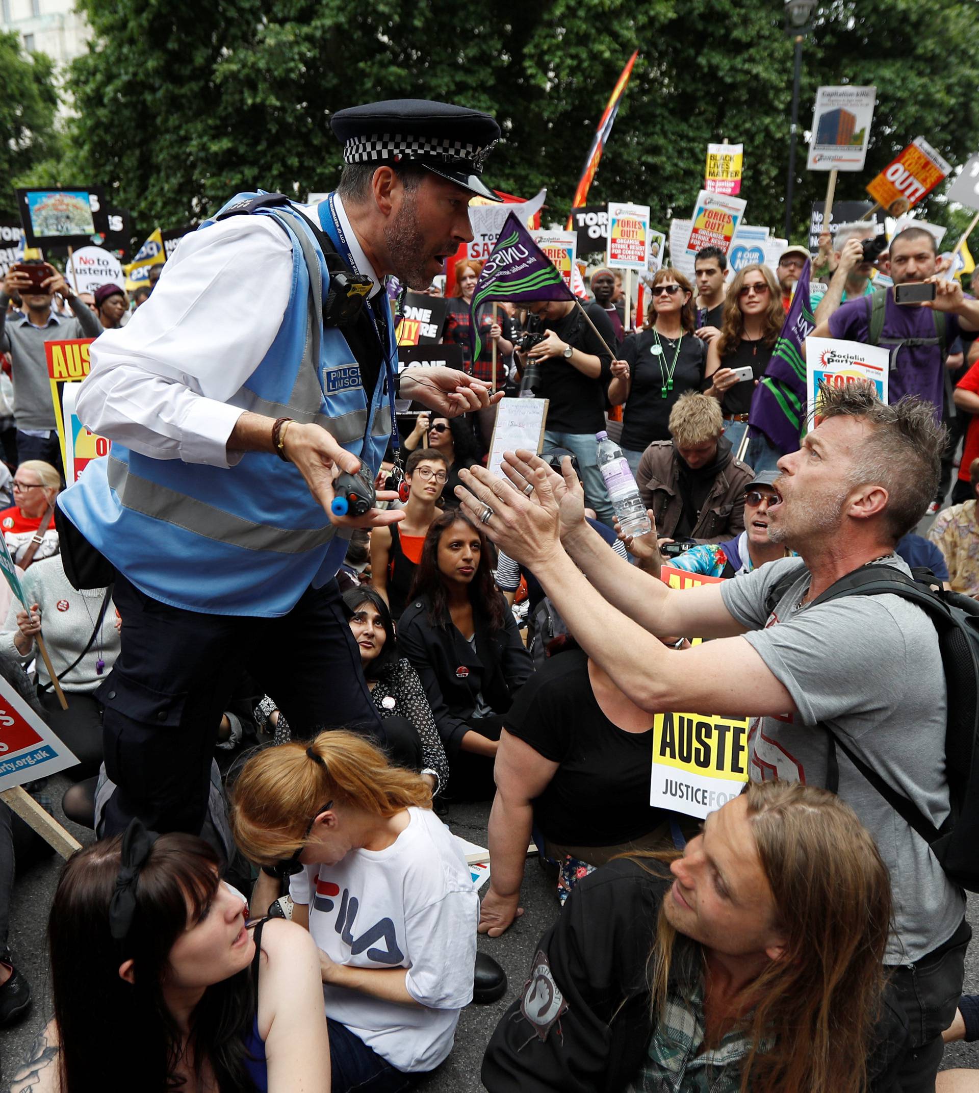 A police officer tells demonstrators to move during a sit-down protest outside Downing Street at an anti-austerity rally and march organised by campaigners Peoples' Assembly, in central London