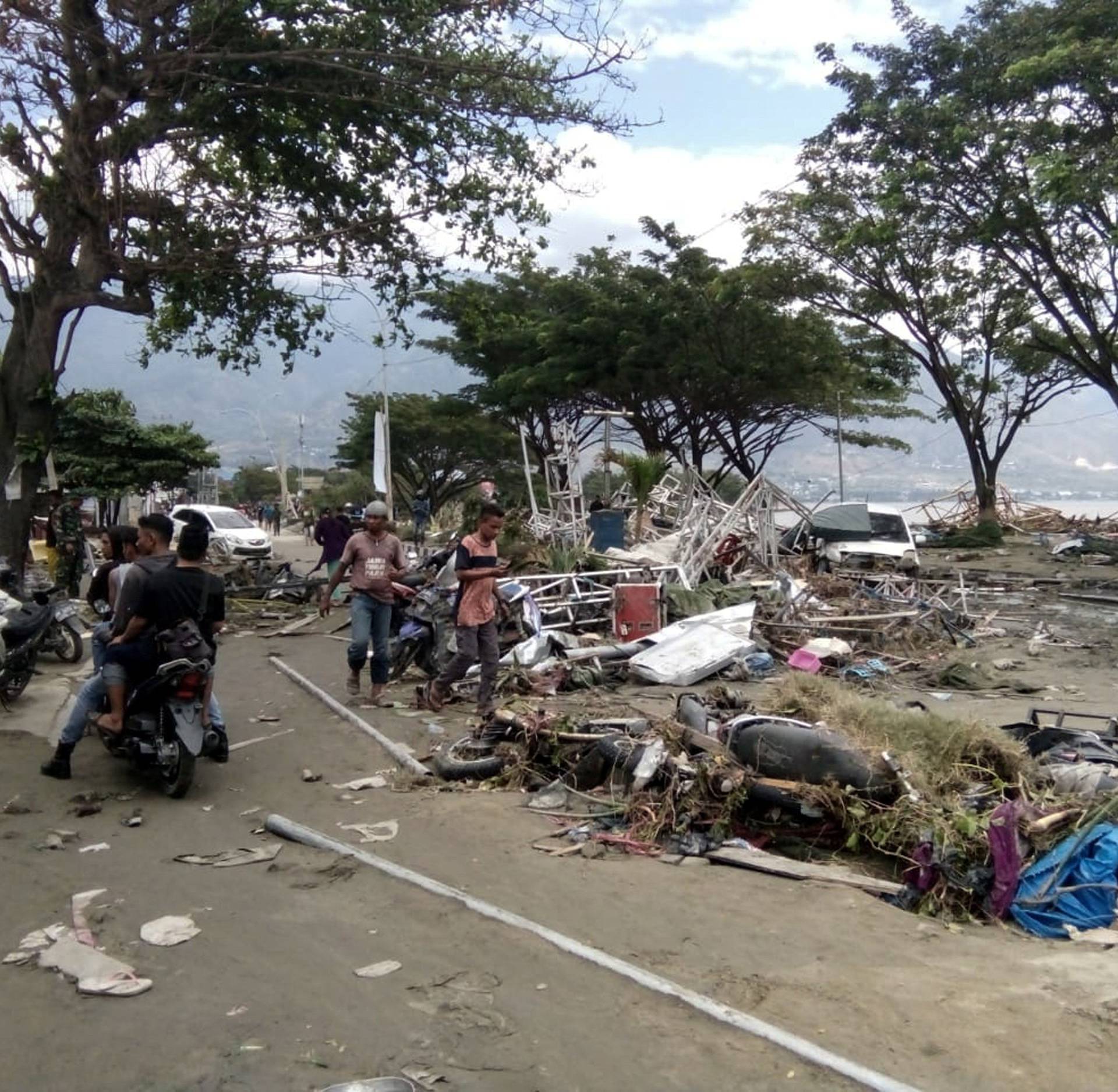 Resident checks dead bodies to find their family at a street after tsunami hit in Palu