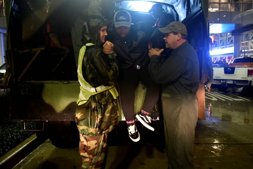 Volunteers unload evacuee Taylor Mitchell from a rescue vehicle at the George R. Brown Convention Center after Hurricane Harvey inundated the Texas Gulf coast with rain causing widespread flooding, in Houston
