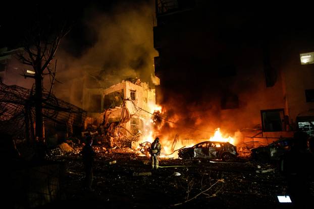Israeli firefighters work to put out a fire on a car at the site of a projectile impact after Iran launched missiles into Israel, following Israeli and U.S. strikes on Iran, in Tel Aviv