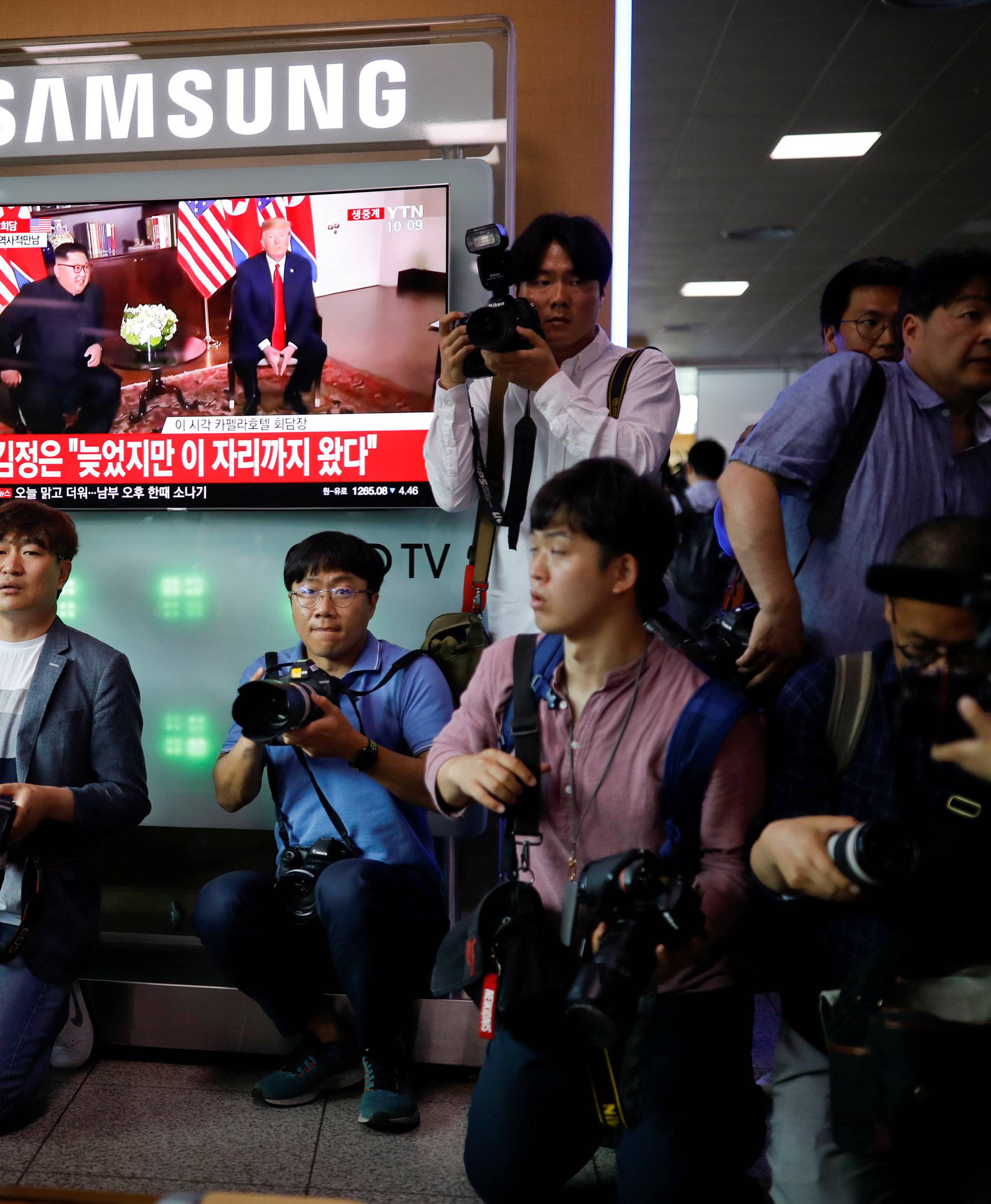 Photographers surround a TV broadcasting a news report on summit between the U.S. and North Korea, in Seoul