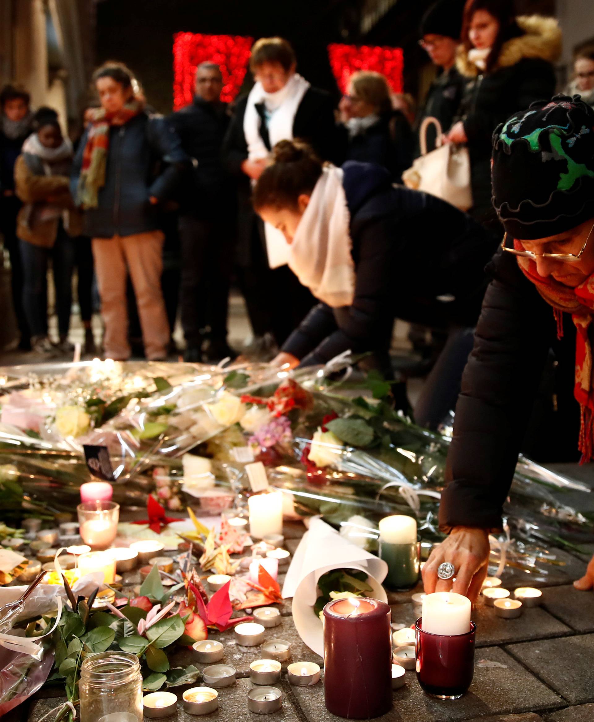 People cry as they light candles in tribute to the victims of the deadly shooting in Strasbourg