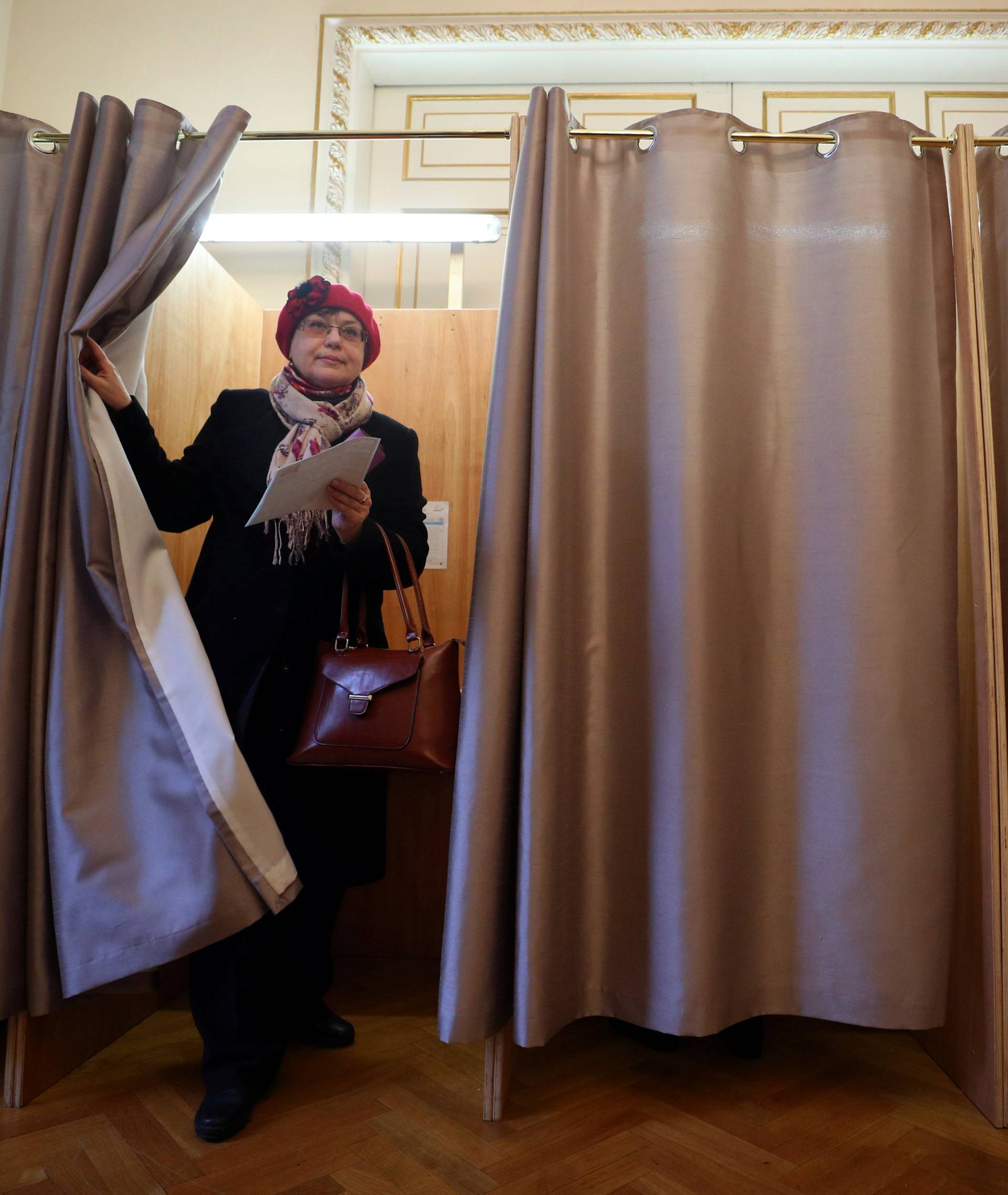 A woman walks out of a voting booth during the presidential election, inside the Russian Embassy in London