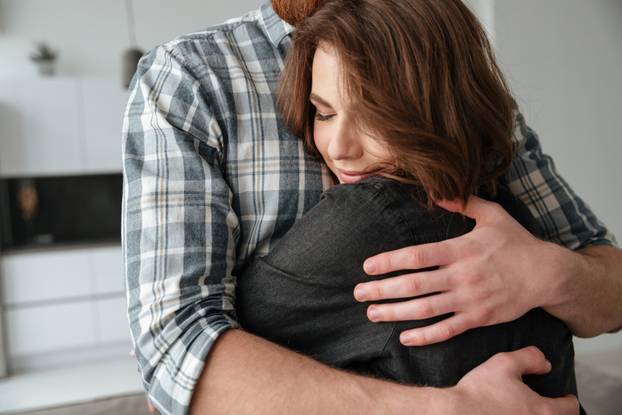 Loving couple hugging in kitchen at home indoors.