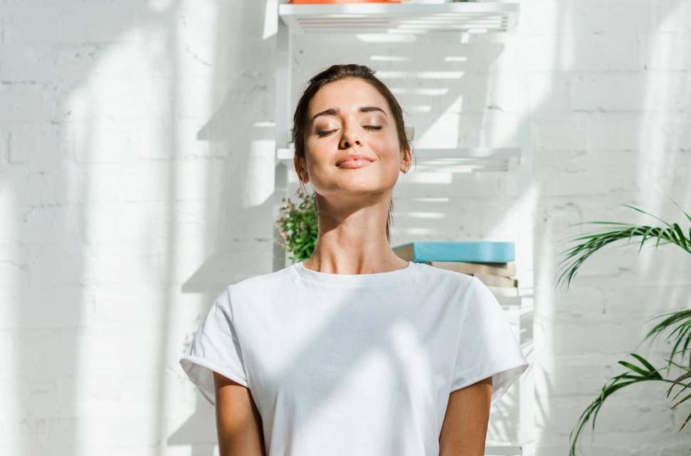 beautiful happy girl with closed eyes practicing yoga in lotus position in bedroom in the morning