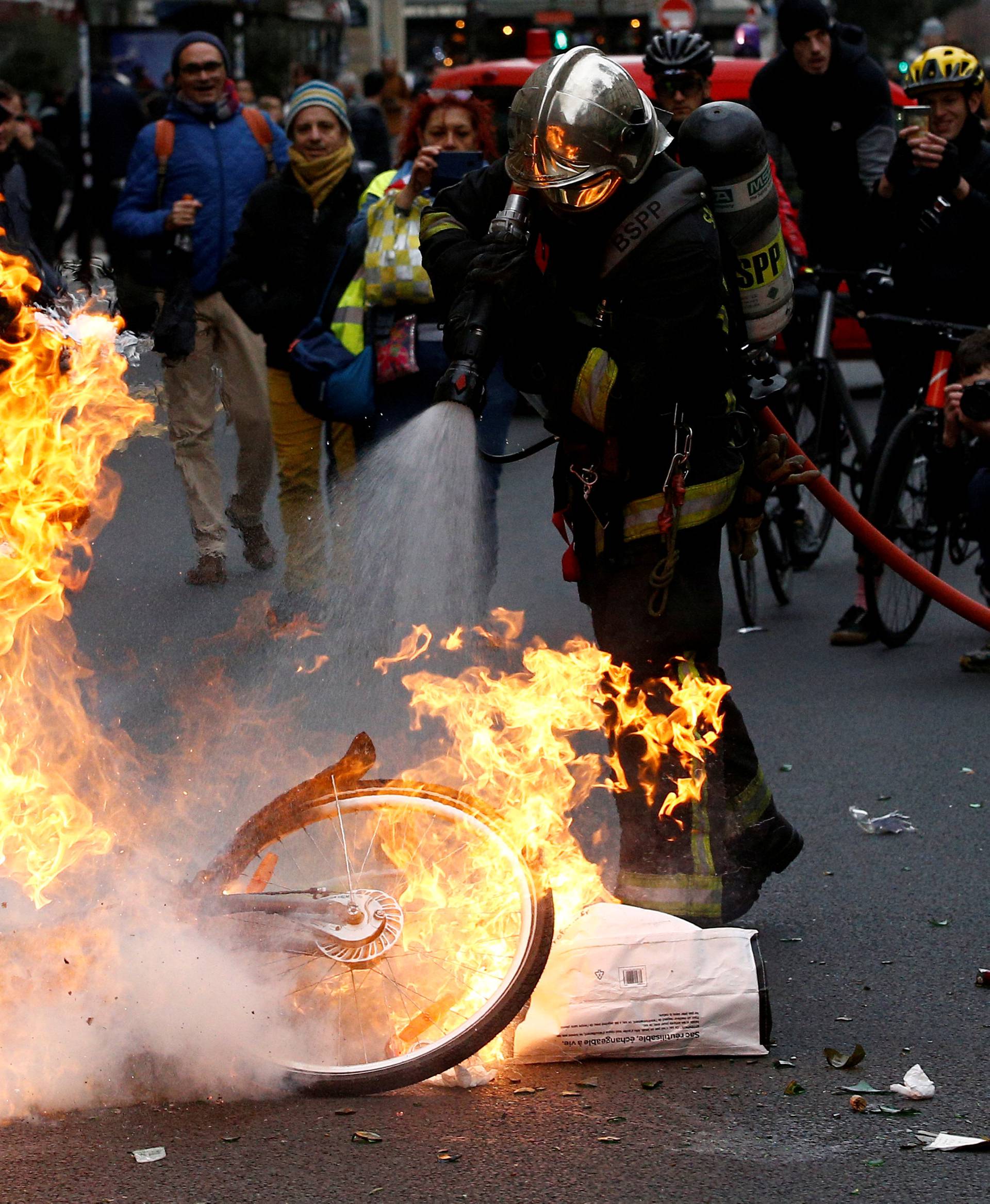 A fireman extinguishes a burning bicycle during clashes with yellow vests protesters as part of a national day of protest by the "yellow vests" movement in Paris