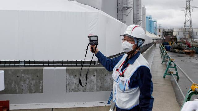 FILE PHOTO: A Tokyo Electric Power Co (TEPCO) employee uses a geiger counter at the company's tsunami-crippled Fukushima nuclear plant