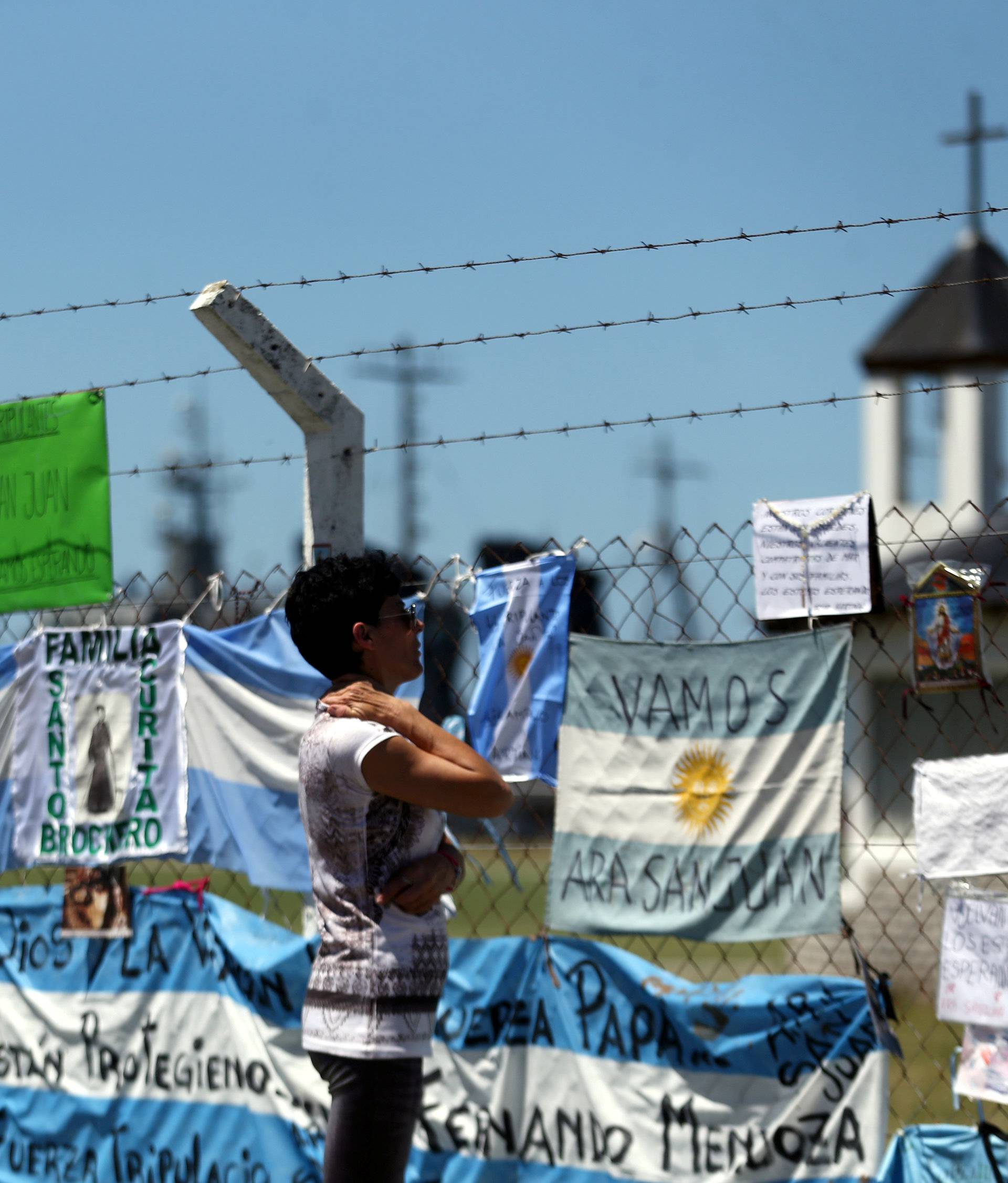 A woman looks at messages and signs in support of the 44 crew members of the missing at sea ARA San Juan submarine, placed on a fence at an Argentine Naval Base in Mar del Plata