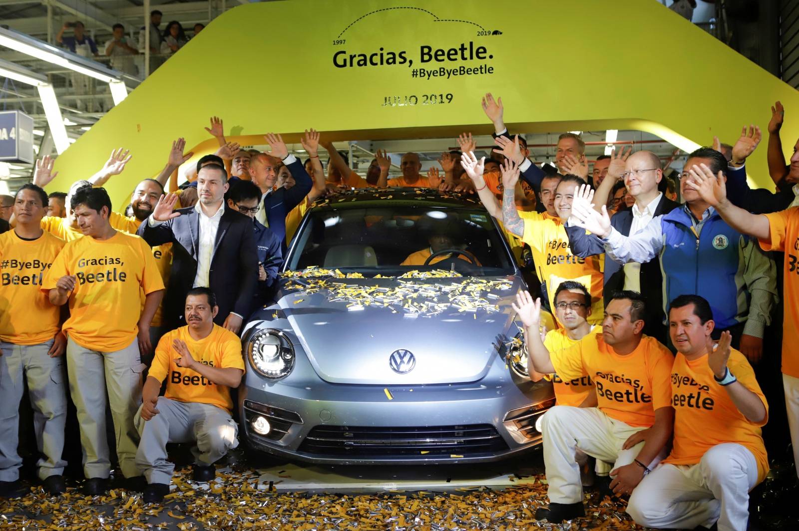 Employees pose for a picture next to a Volkswagen Beetle car during a ceremony marking the end of production of VW Beetle cars, at company's assembly plant in Puebla