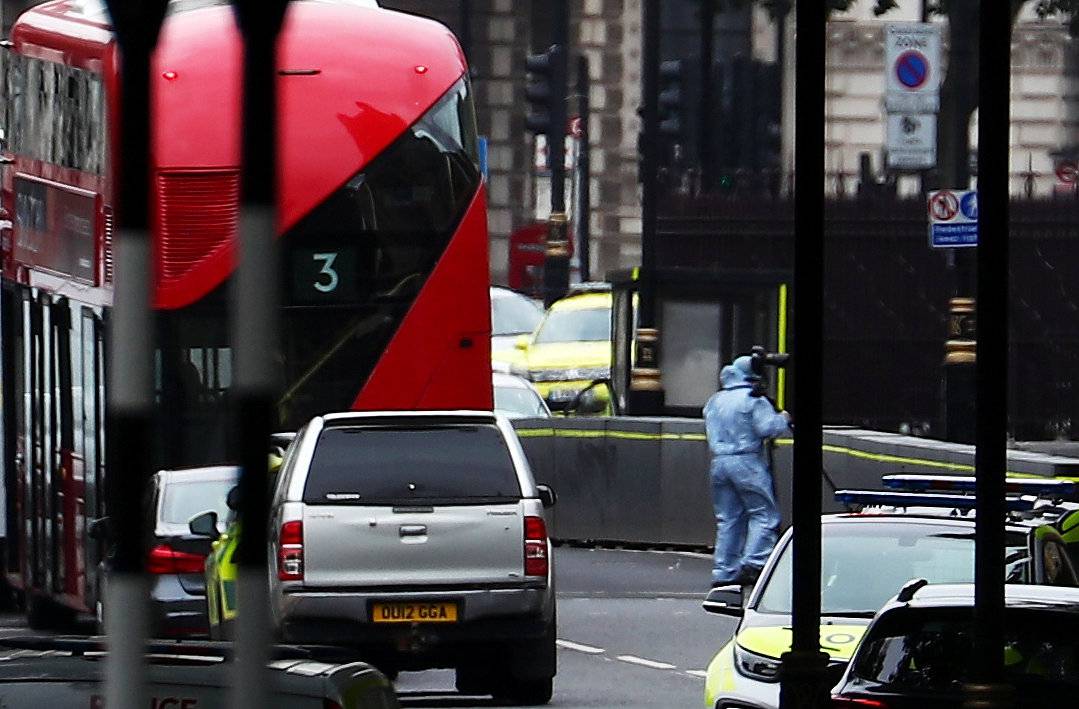 A forensics investigator works at he scene after a car crashed outside the Houses of Parliament in Westminster, London