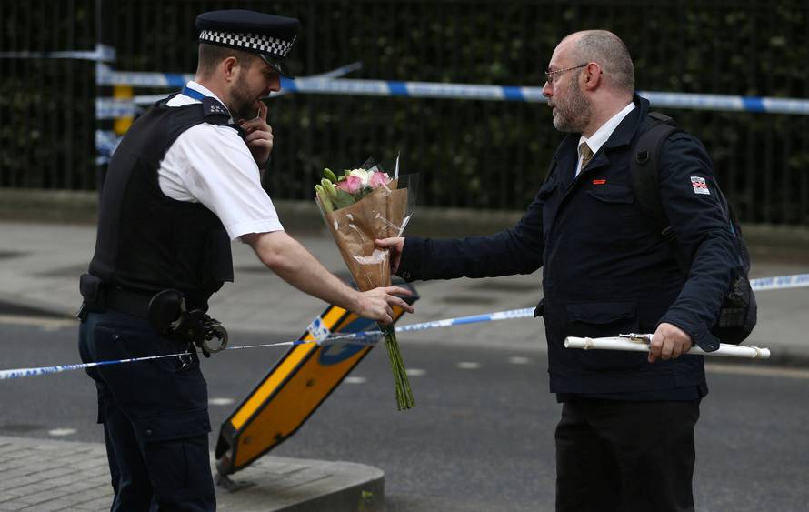 A man gives a police officer a floral tribute after a knife attack in Russell Square in London