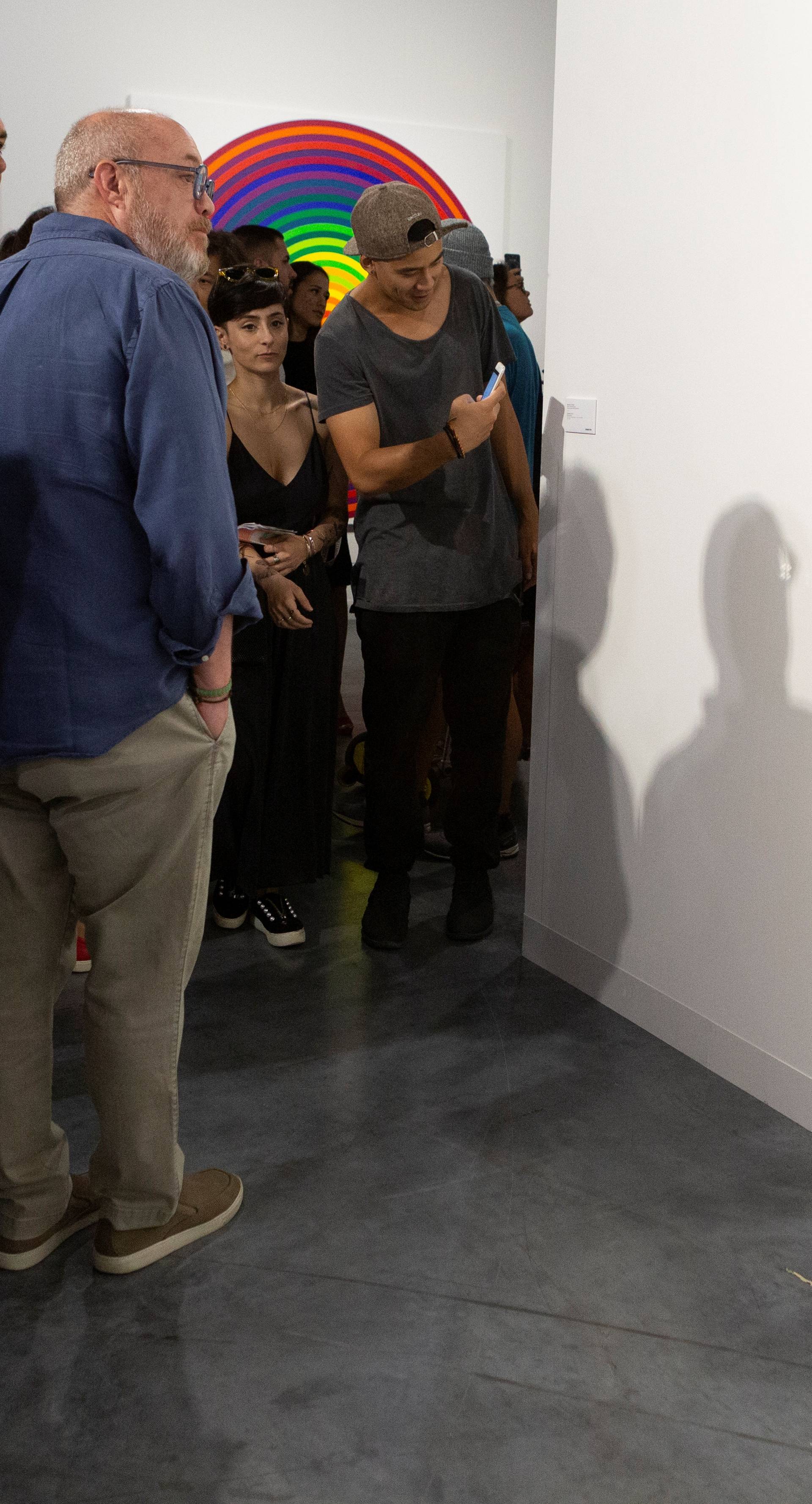 Art Basel visitors use their phones in front of the wall where the artwork 'Comedian' by the artist Maurizio Cattelan was exhibited in Miami Beach