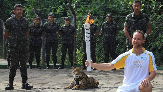 Brazilian physiotherapist Igor Simoes Andrade poses for picture next to jaguar Juma as he takes part in the Olympic Flame torch relay in Manaus