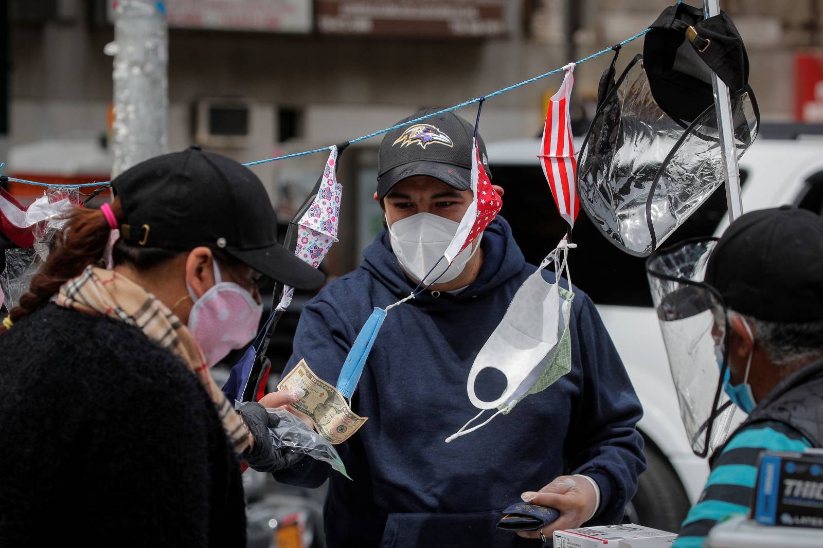 A man purchases a face mask from a street vendor, during the outbreak of the coronavirus disease (COVID-19), in the Corona section of Queens, New York