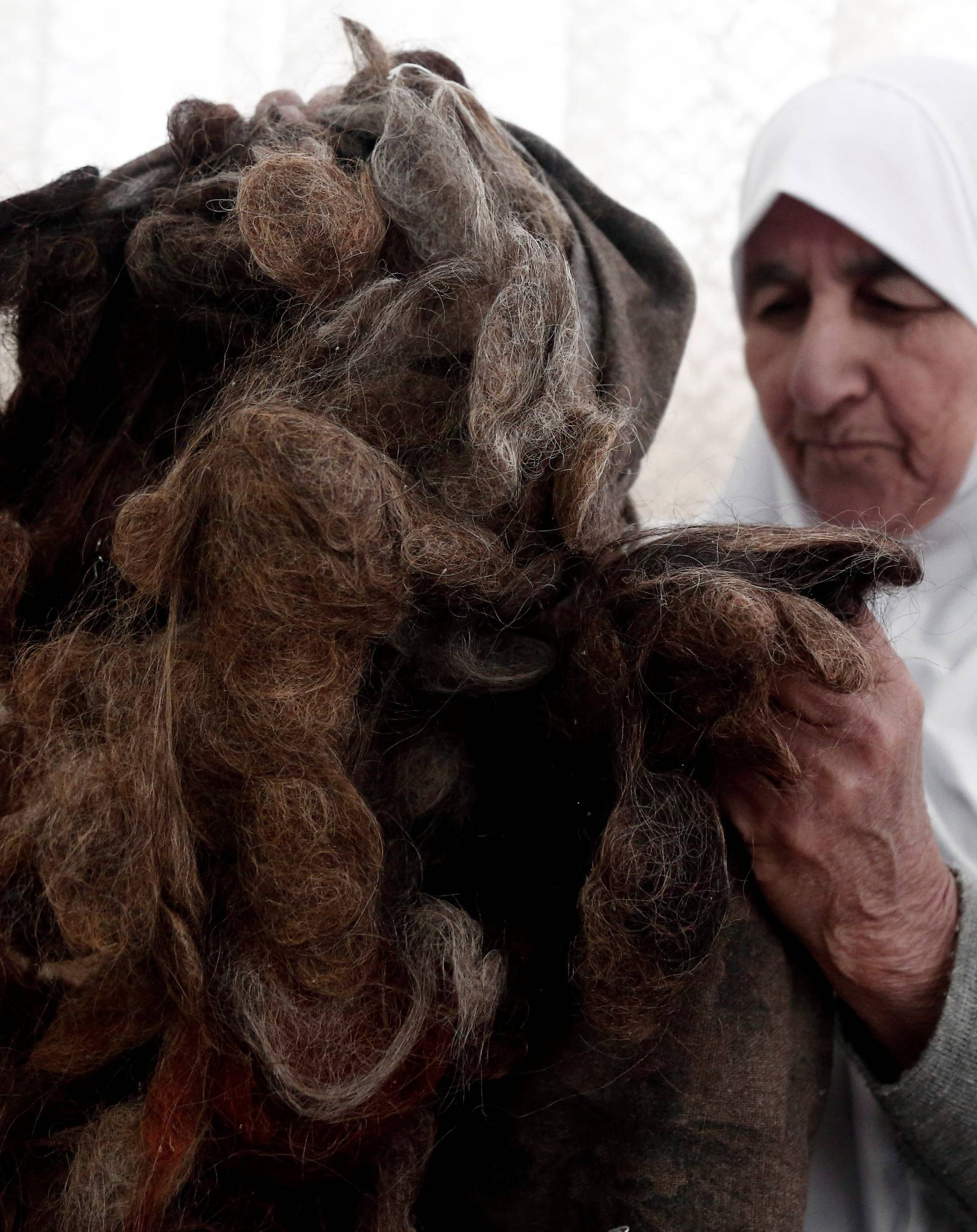 Ezzeya Daraghmeh, an 82-year-old Palestinian woman who said she has kept parts of her hair she cut over 67 years, holds her collected hair as she stuffs it in a pillow, in the West Bank town of Tubas