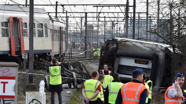 Rescuers and police officers stand next to the wreckage of a passenger train after it derailed in Kessel-Lo near Leuven