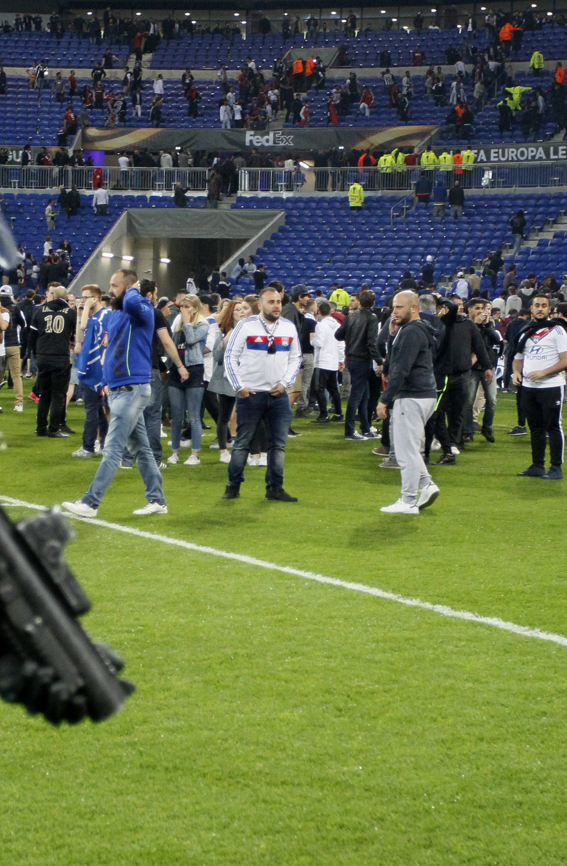 Police officers as Lyon fans invade the pitch and fans clash in the stands