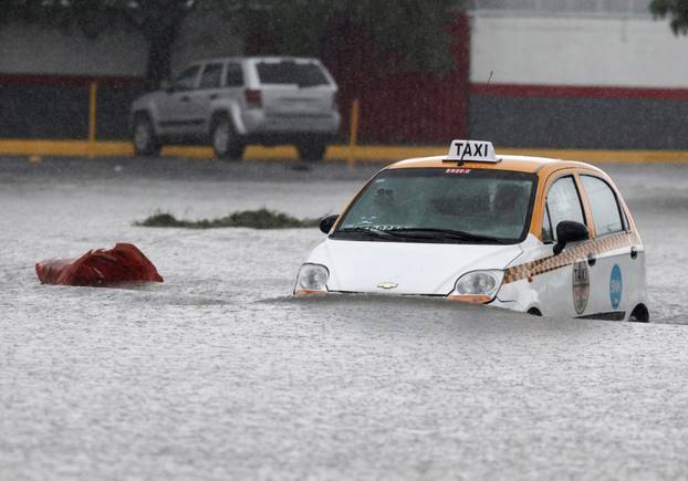 A taxi driver is seen crossing a flooded street during the Storm Hanna in Apodaca