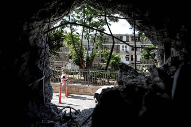 FILE PHOTO: A woman is seen through a wall of a residential building which was damaged by a rocket launched overnight from the Gaza Strip, in Ashkelon