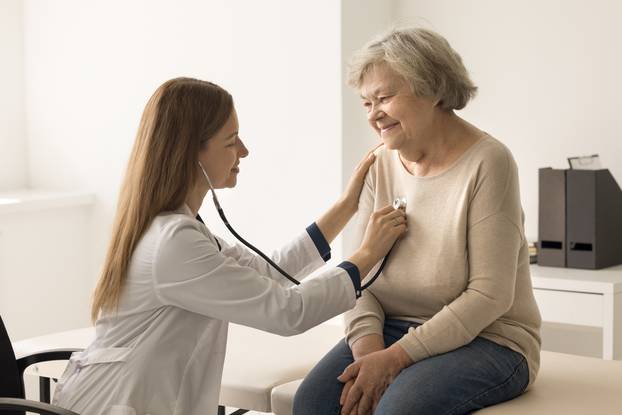 Cardiologist,In,Coat,Examines,Older,Woman,In,Clinic,,Listen,To