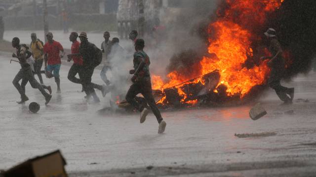 People run at protest as barricades burn during rainfall in Harare