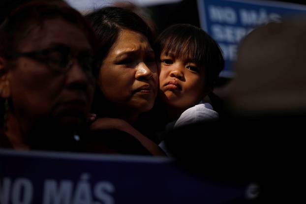 A child embraces a woman as demonstrators hold signs against the Trump administration policy of separating migrant children from their parents at the border during a demonstration outside of City Hall in Los Angeles