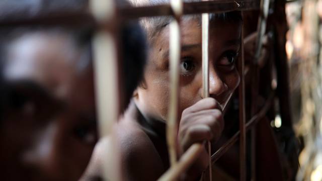 Rohingya refugee child looks through the fence at a refugee camp in Cox's Bazar