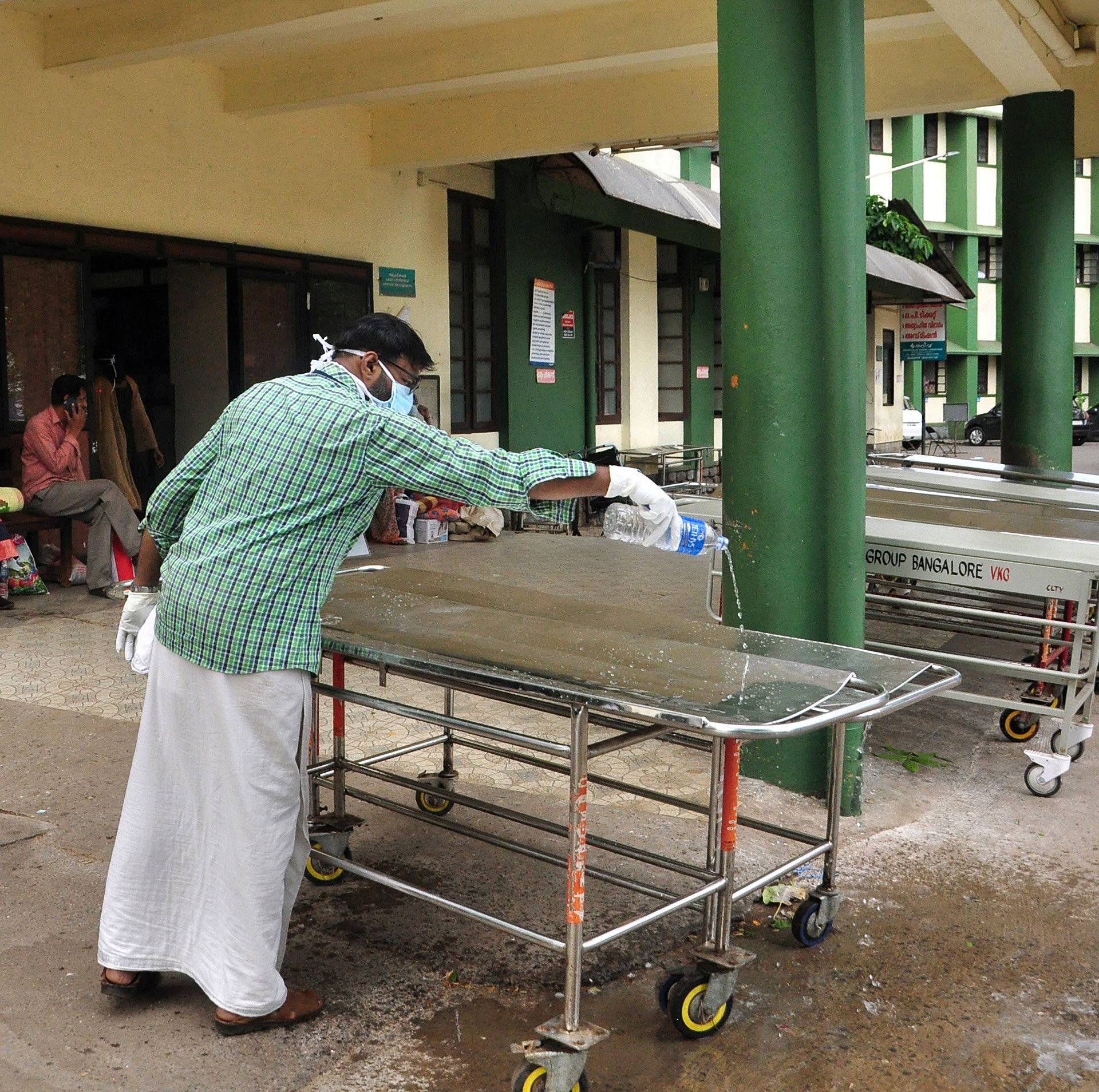 A member of an NGO cleans a cot outside the casualty ward at a hospital in Kozhikode