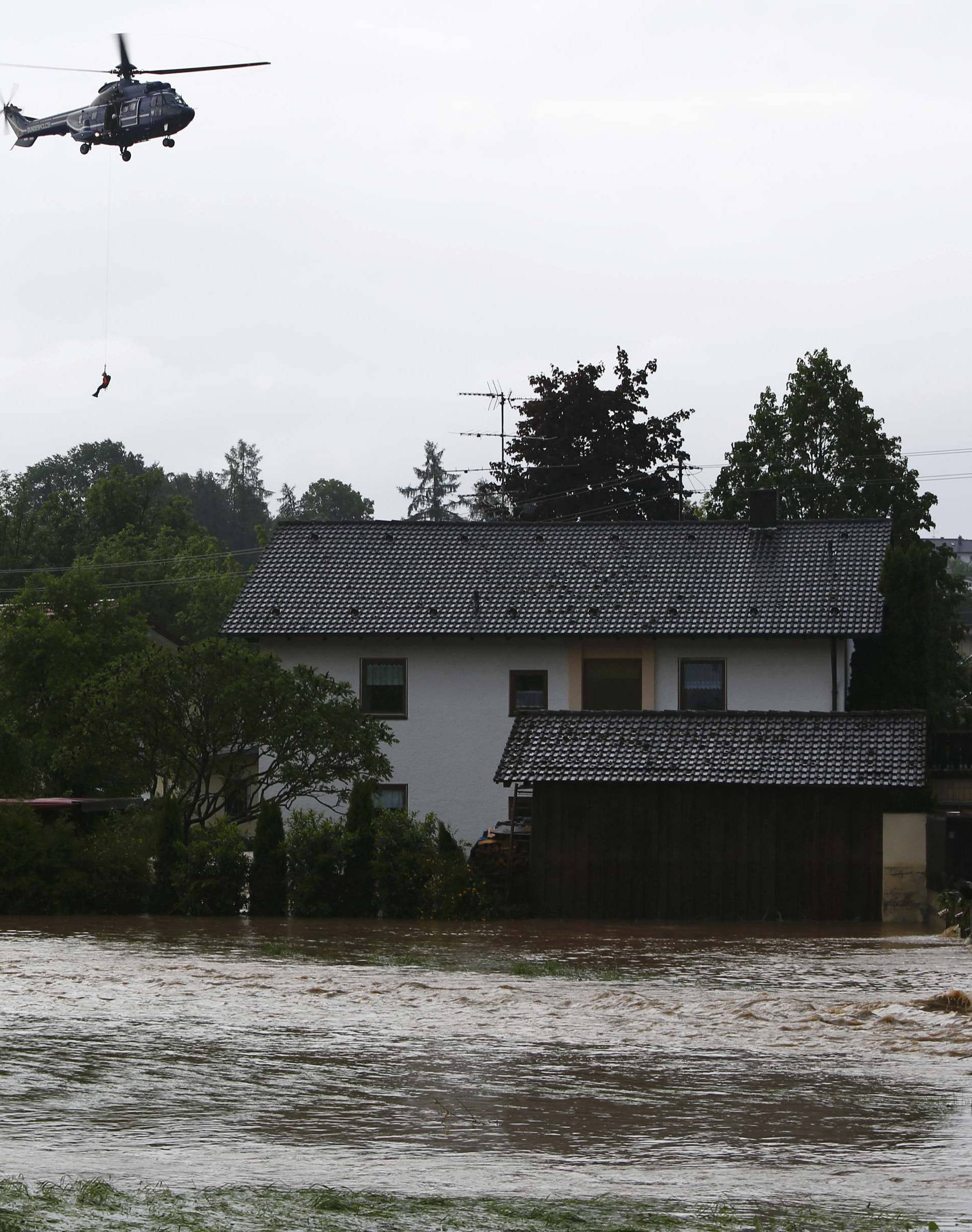 A helicopter carries a person during a rescue operation in the Bavarian village of Triftern