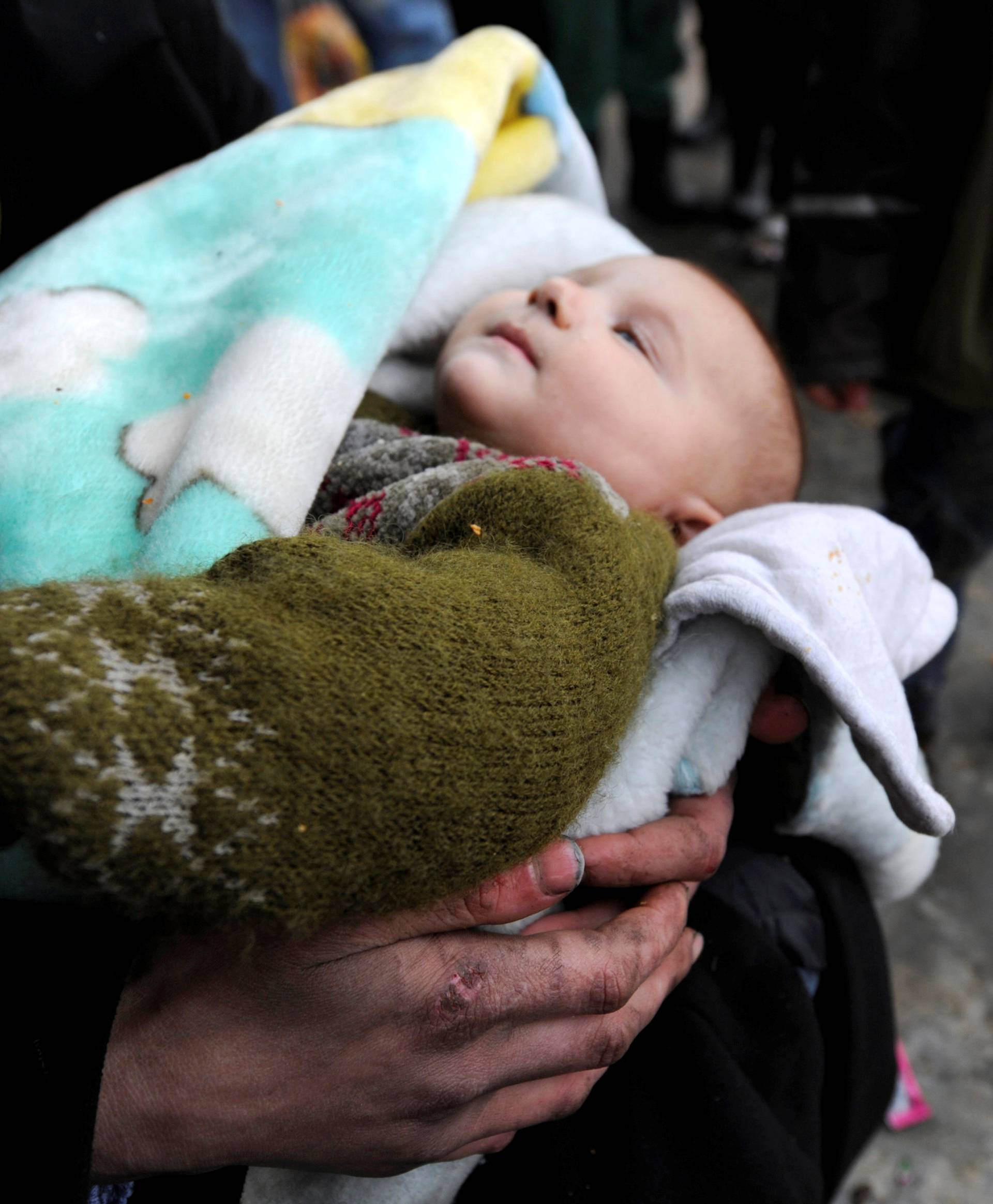 A Syrian evacuated from eastern Aleppo carries her baby in government controlled Jibreen area in Aleppo