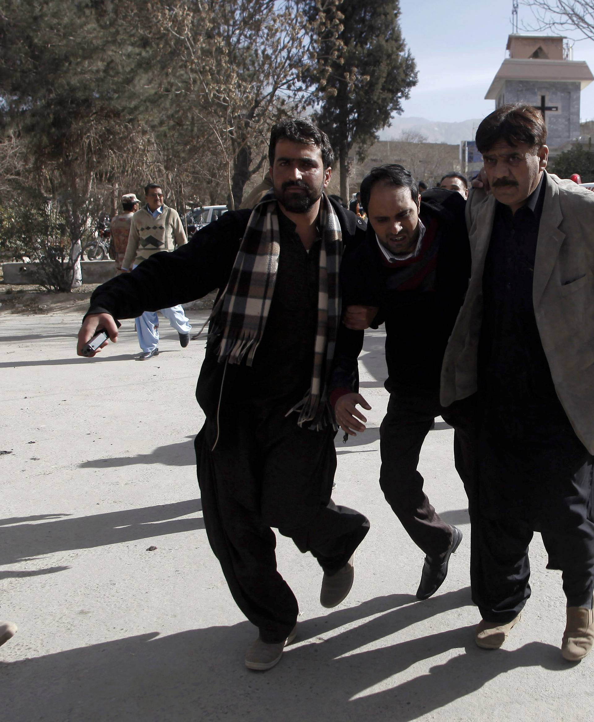 Plain-clothed security officers help an injured man after gunmen attacked the Bethel Memorial Methodist Church in Quetta