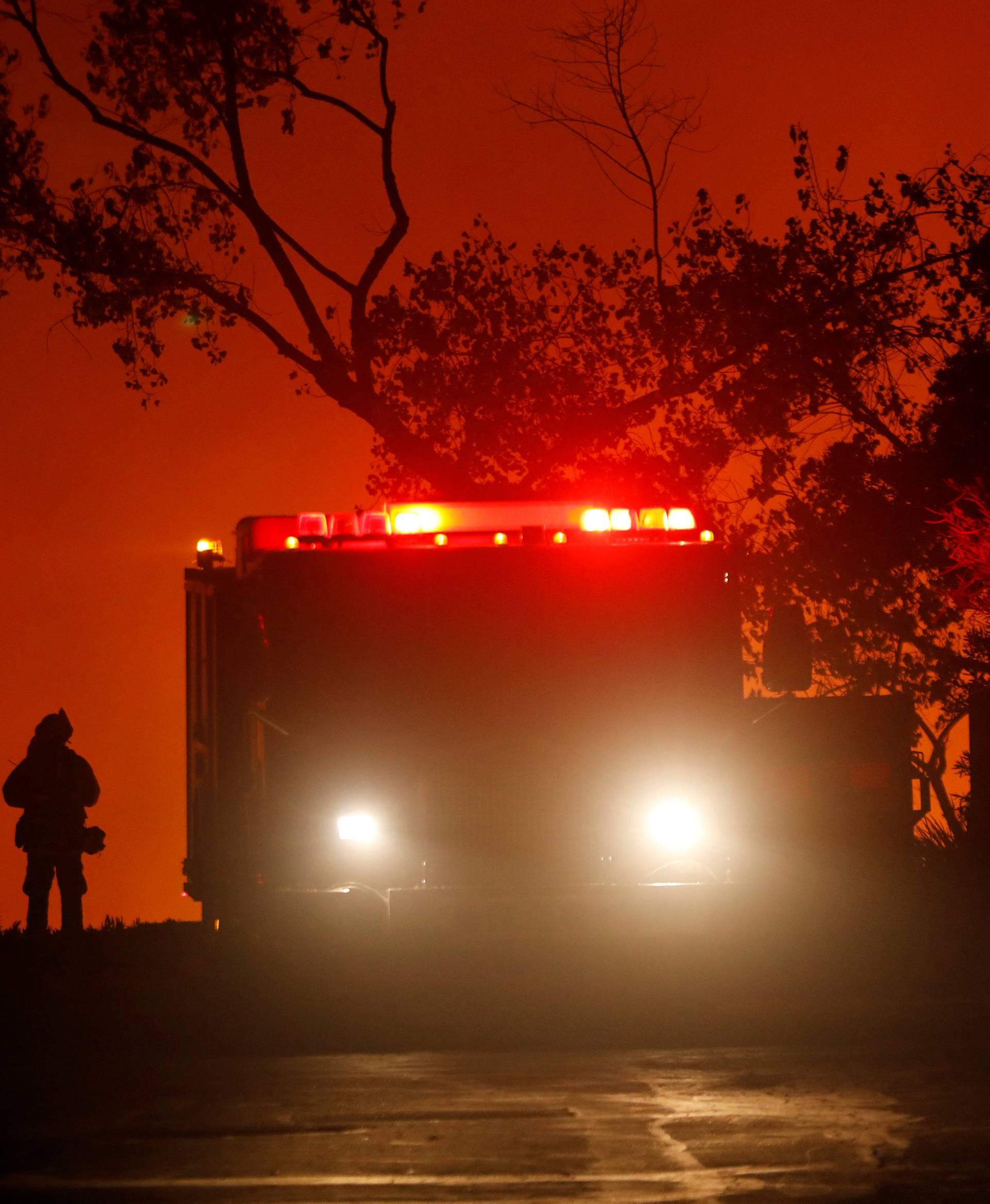A firefighter waits at the top of a hill to battle the Lilac Fire, a fast moving wild fire in Bonsall, California