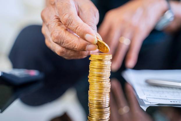 Closeup,Of,Elderly,Man,Hand,Stacking,Golden,Coins,On,The