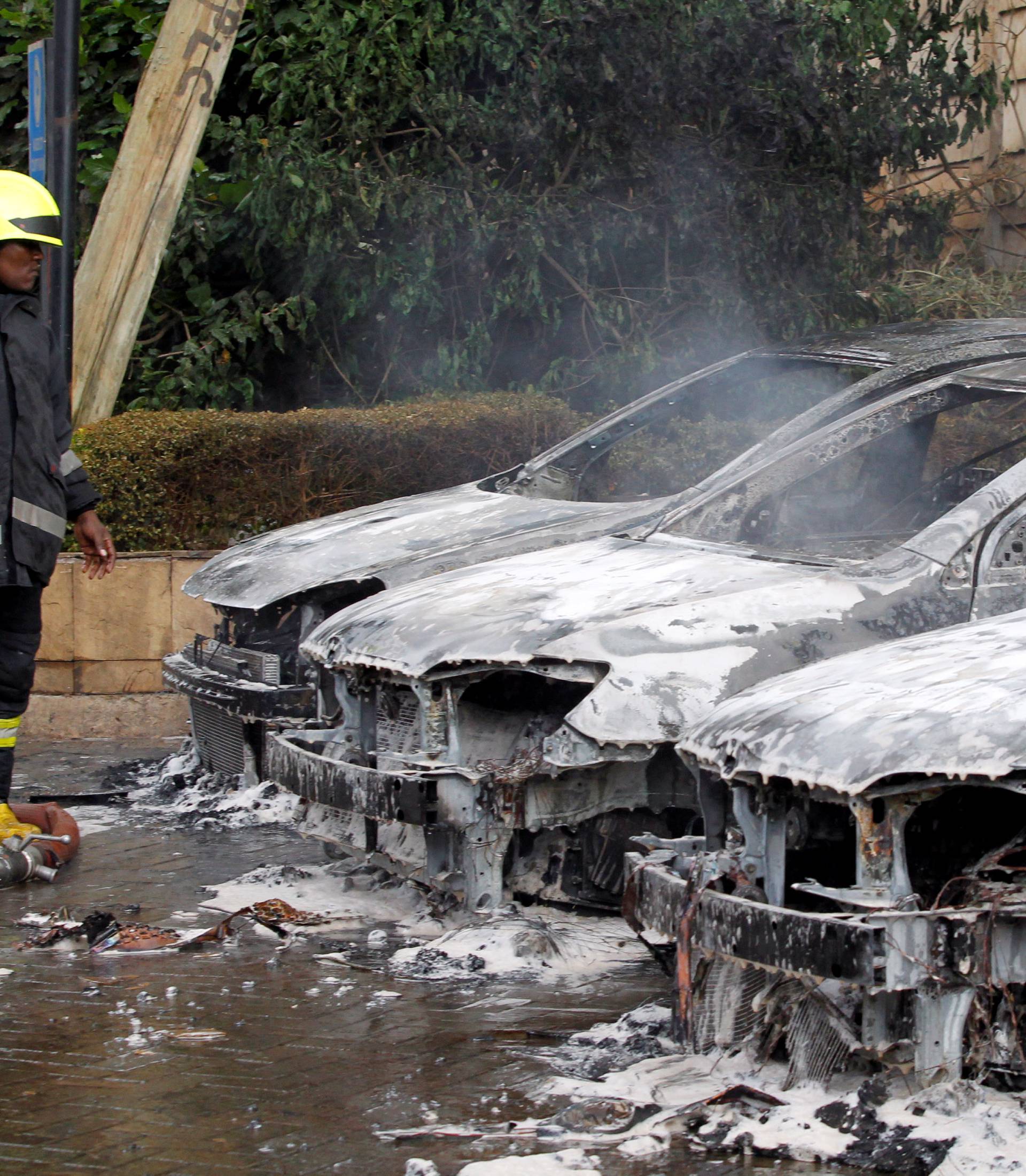 A firefighter stands near burnt vehicles at the scene where explosions and gunshots were heard at the Dusit hotel compound, in Nairobi
