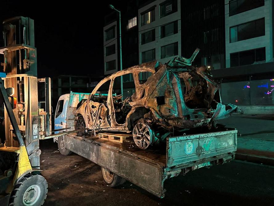 A truck carries a burned-out car that was hit by an Israeli airstrike in Beirut